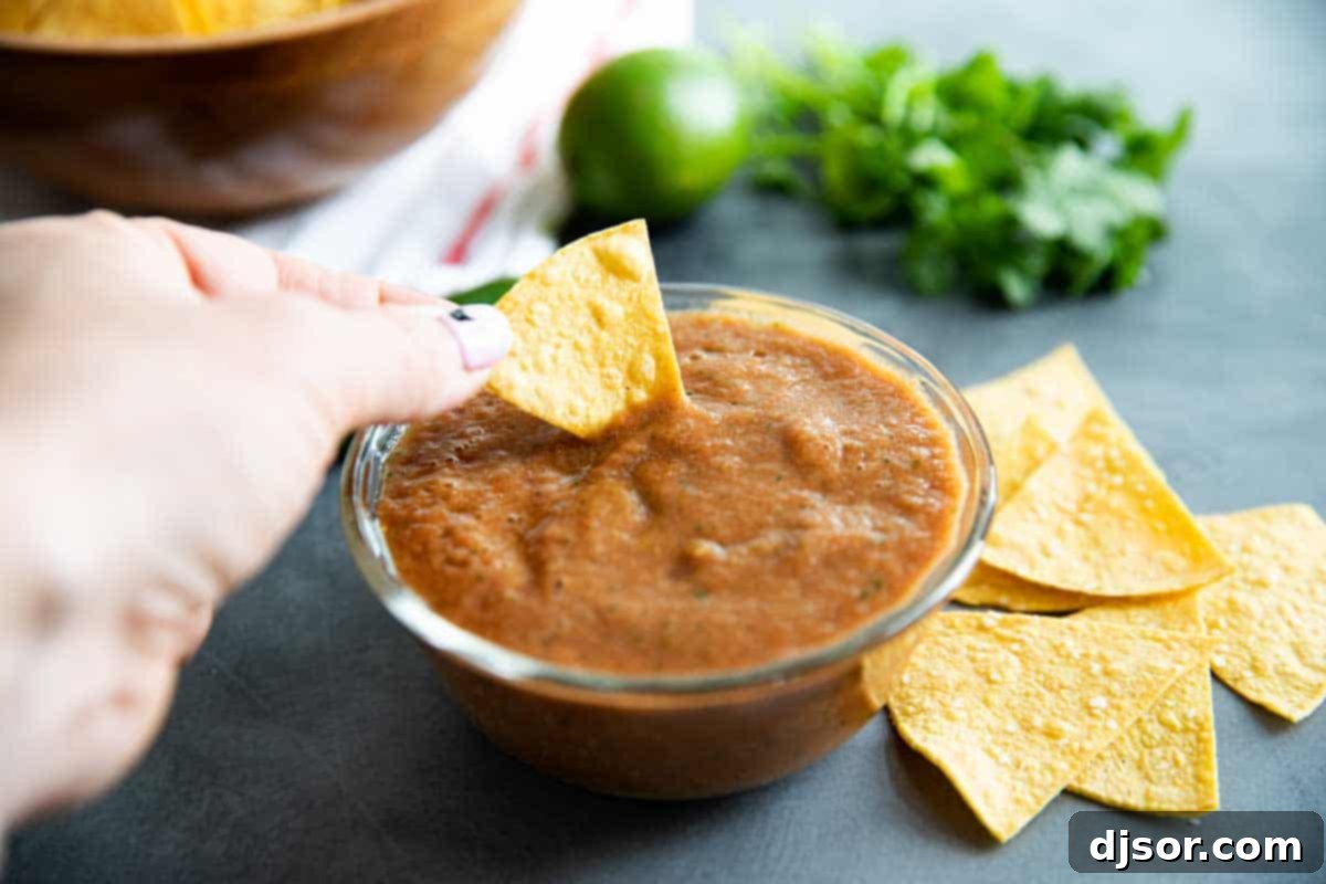 A chip being dipped into a bowl of vibrant homemade salsa, ready to be enjoyed.