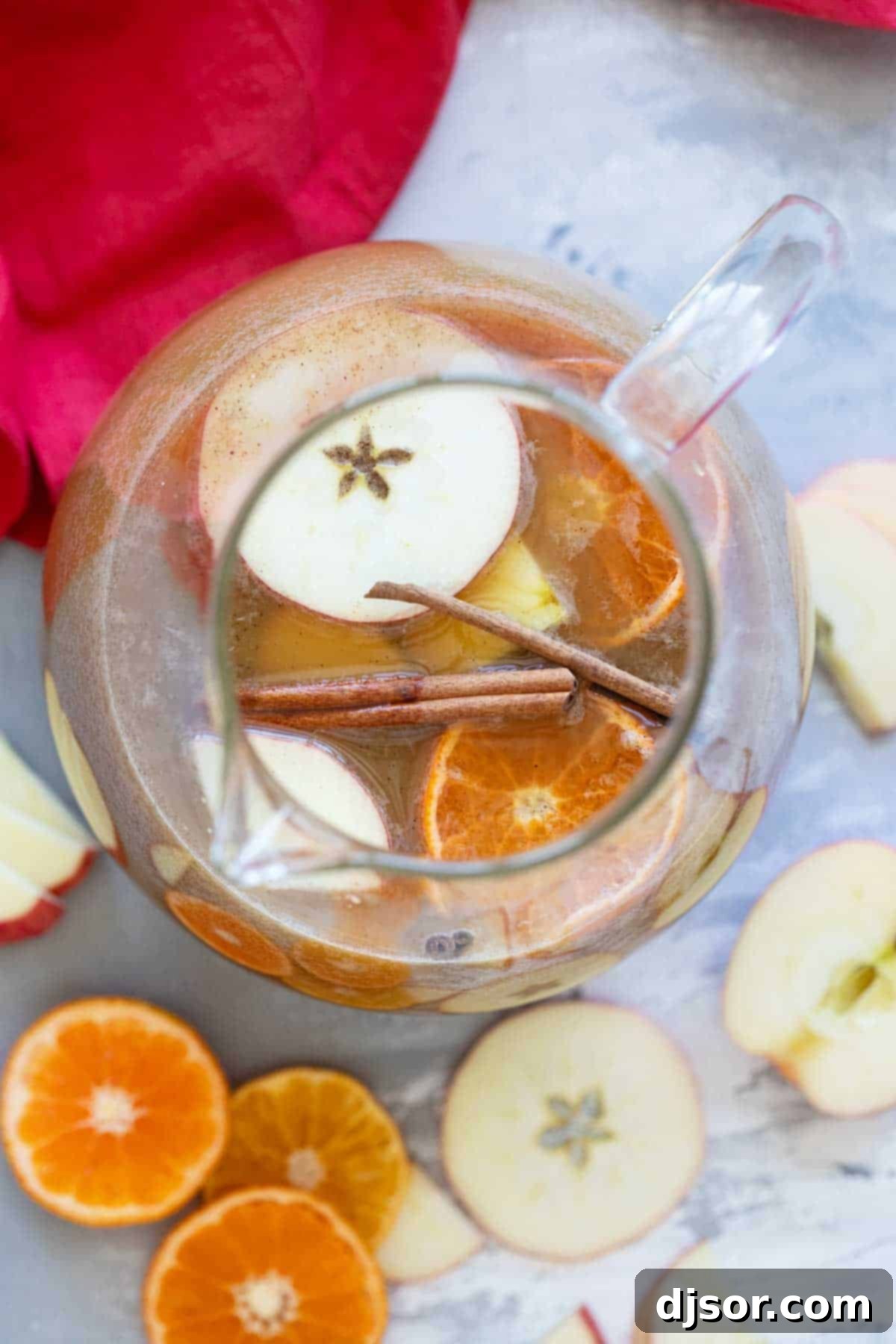 Pitcher filled with Apple Cider Punch, garnished with apple slices and orange slices.