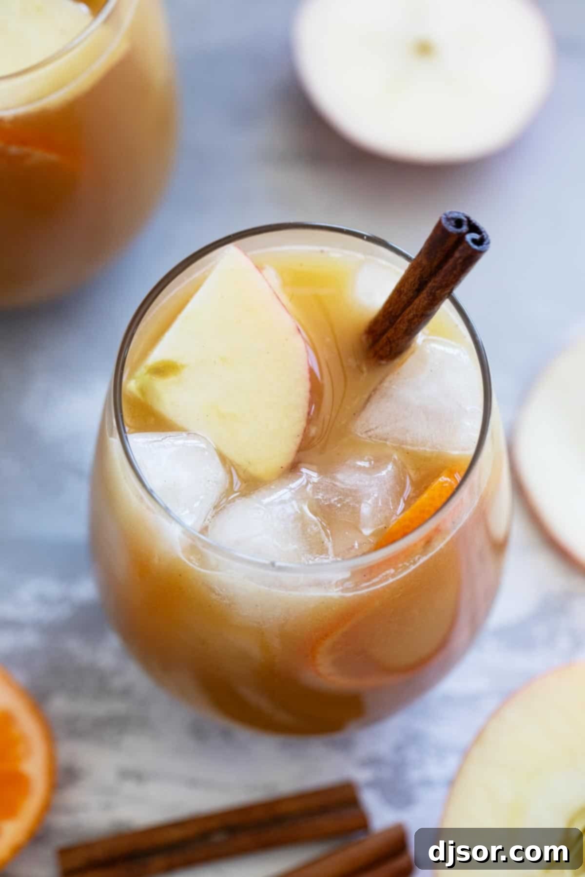 Glass of Apple Cider Punch garnished with apple slices and a cinnamon stick.