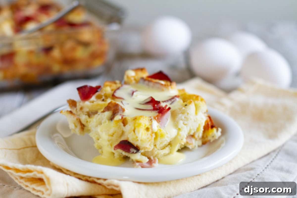 Eggs benedict made easy!! An Eggs Benedict Casserole is an overnight casserole with the flavors of eggs benedict that is served with an easy blender hollandaise sauce poured over the top. A perfectly portioned slice of Eggs Benedict Casserole, generously drizzled with homemade blender hollandaise sauce, served on a white plate.