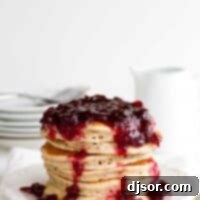 Tangy Cranberry Cloud Cakes 4 stack of Cranberry Pancakes on a white plate with white background