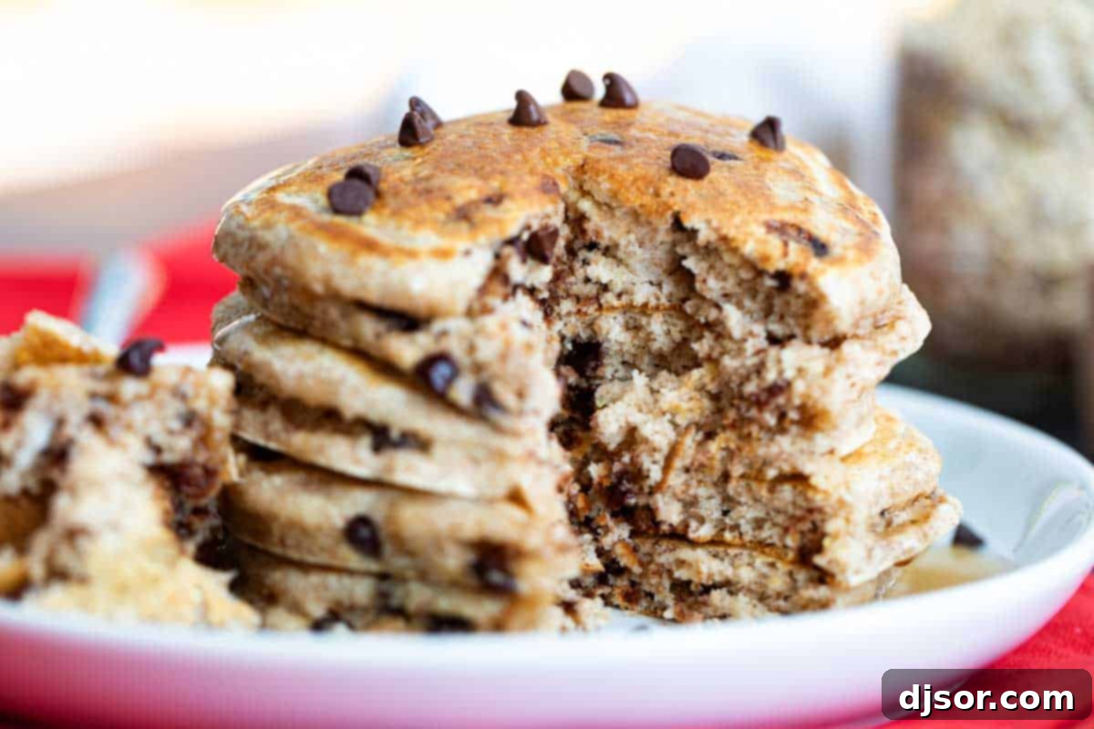 An easy recipe for a healthier breakfast choice, these Oatmeal Pancakes with Chocolate Chips are made with oats, whole wheat, and the perfect touch of sweetness from mini chocolate chips. oatmeal pancakes with chocolate chips with a bite taken