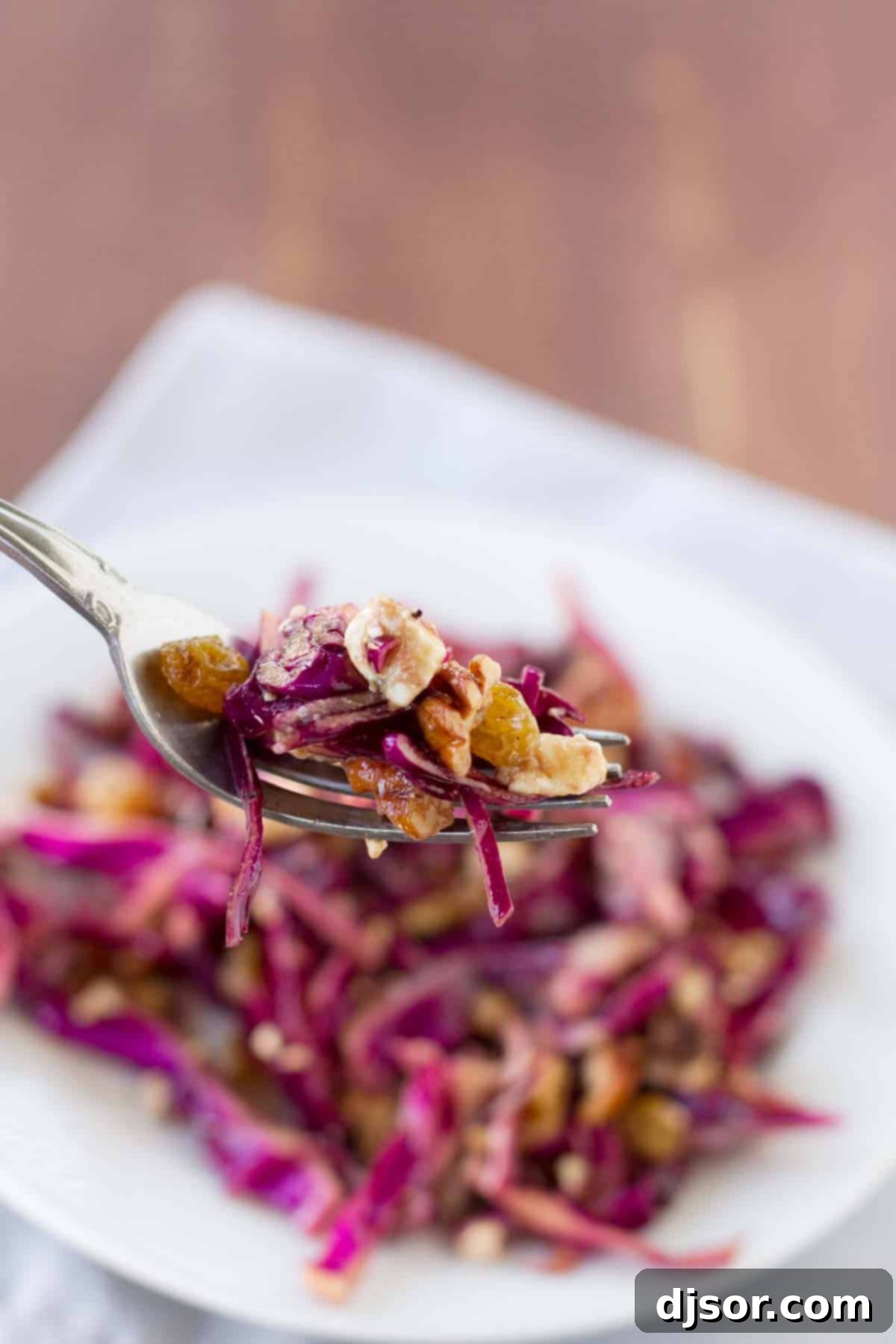 Vibrant Cabbage Slaw 3 bite of cabbage salad with golden raisins and walnuts, highlighting crunchy textures