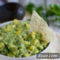 Island-Inspired Avocado Dream 2 Bowl filled with Tropical Guacamole with a tortilla chip.