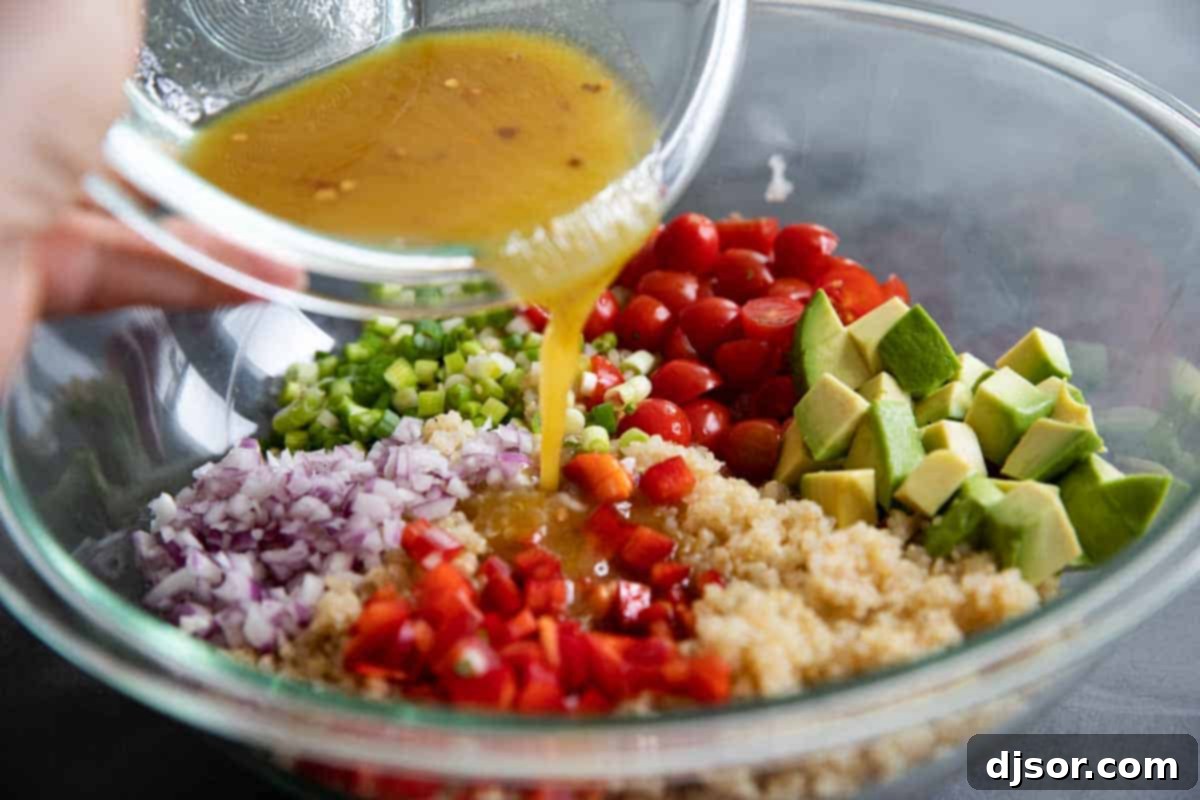Fresh ingredients laid out for a quinoa salad, including cherry tomatoes, bell peppers, red onion, avocado, and lime.