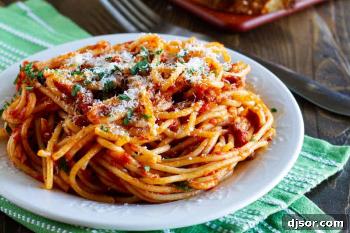 Delicious Easy Spaghetti Meat Sauce ready to serve. Easy Spaghetti Meat Sauce with pasta on a plate, garnished with fresh herbs and Parmesan cheese.