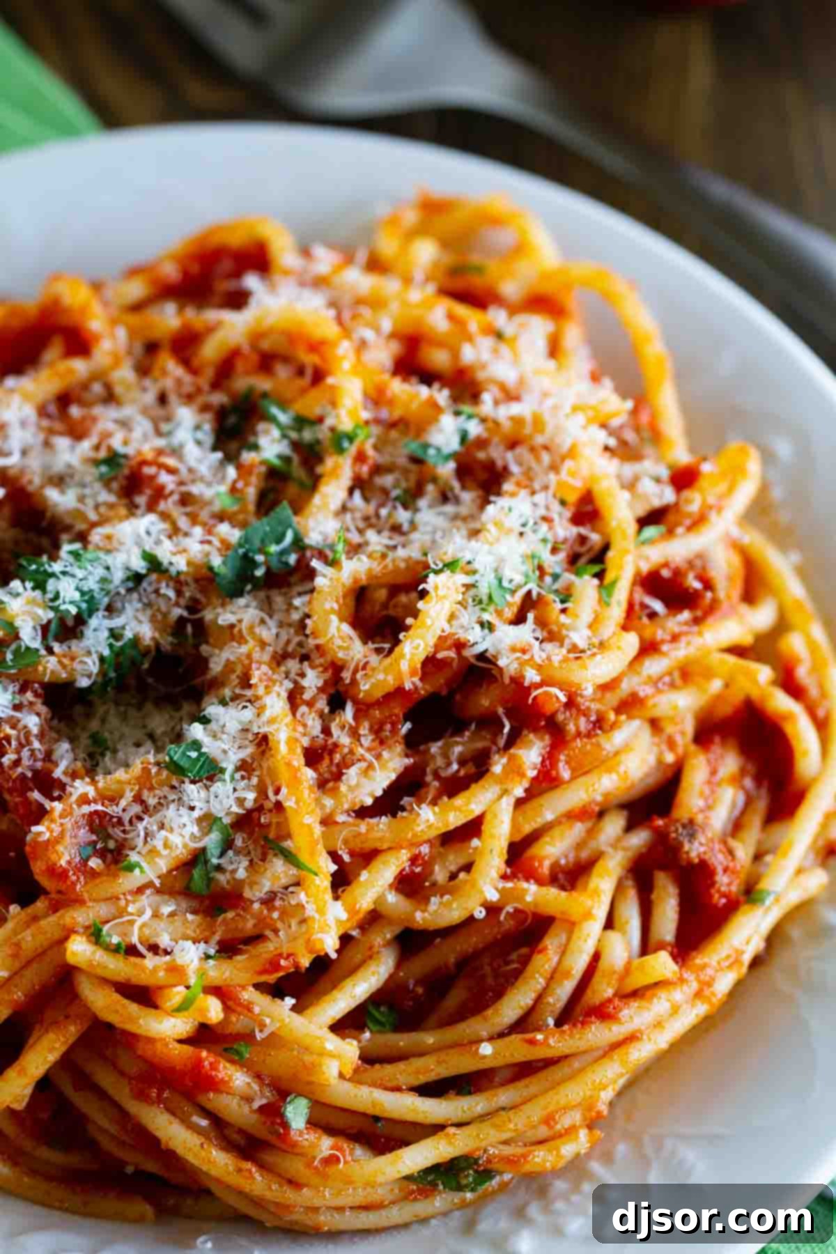 Finished Easy Spaghetti Meat Sauce ready to enjoy, garnished to perfection. A serving of spaghetti with rich meat sauce, elegantly topped with freshly grated Parmesan cheese and a sprig of fresh parsley.