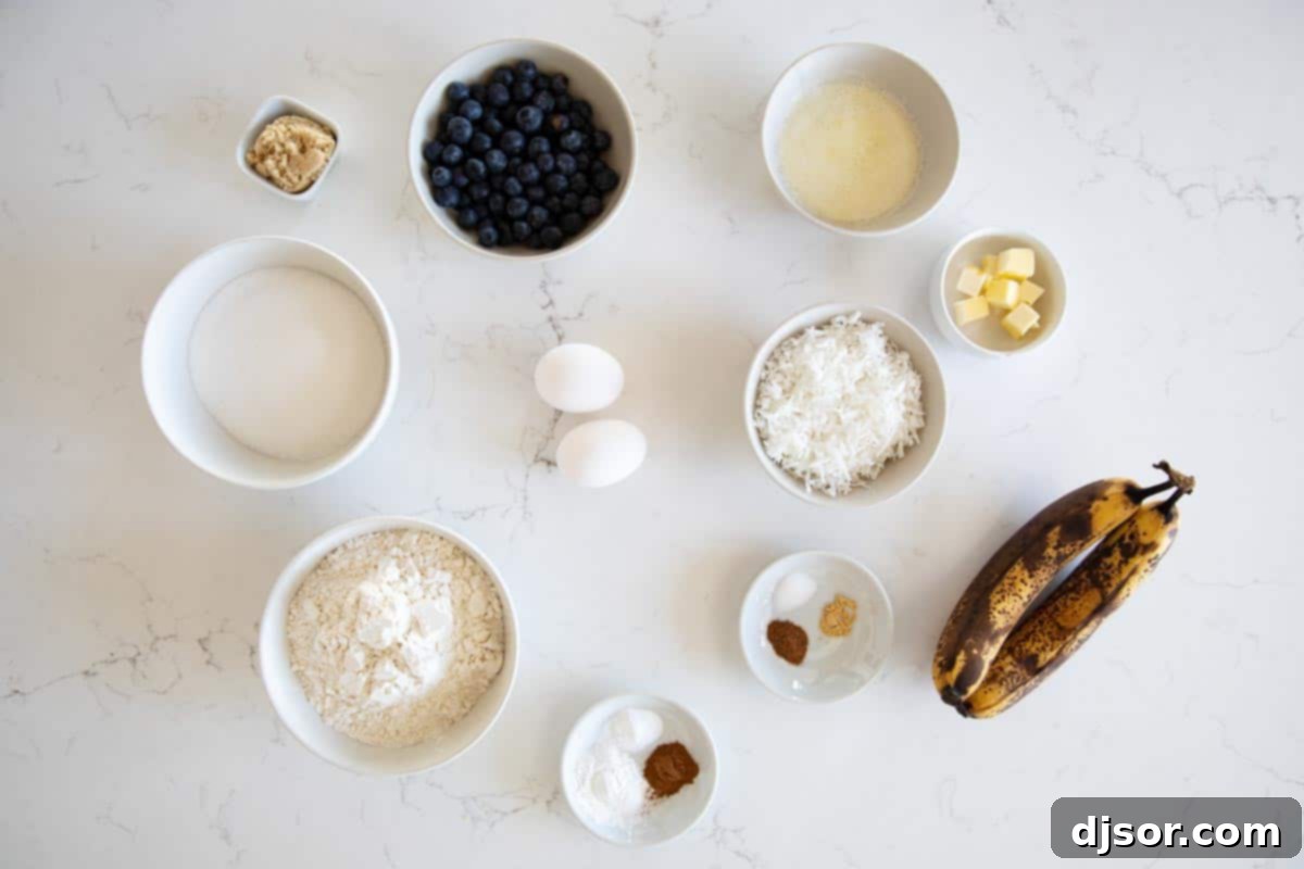 Make a change from your typical banana bread with this Blueberry Banana Bread with Coconut that is filled with fresh berries and topped with a crunchy streusel topping. A flat lay photograph displaying all the fresh and dry ingredients meticulously laid out for making the delicious blueberry banana bread with coconut, including ripe bananas, fresh blueberries, flour, sugar, and spices.