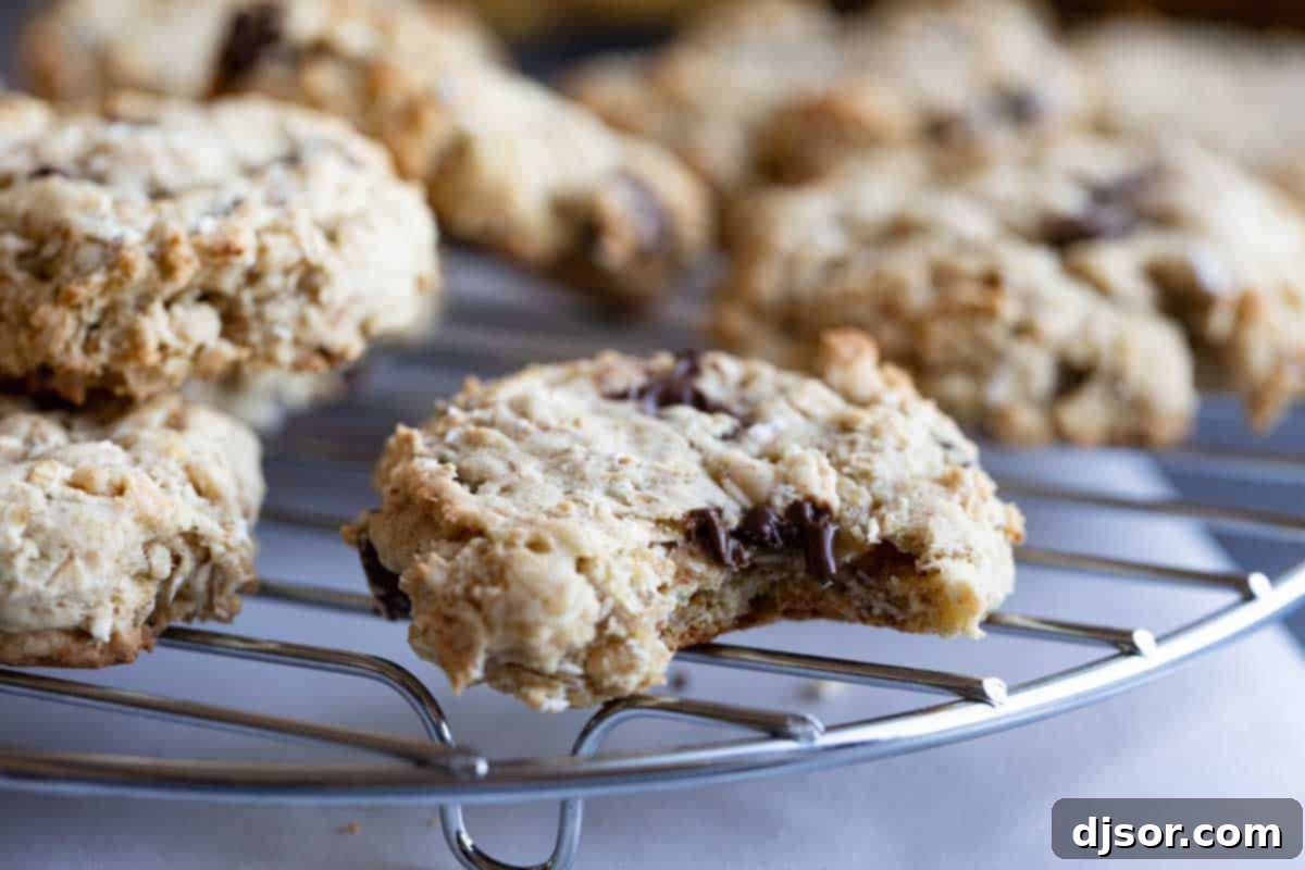 Close-up of a banana oatmeal cookie on a cooling rack with a bite taken out, showing its chewy interior and chocolate chips.