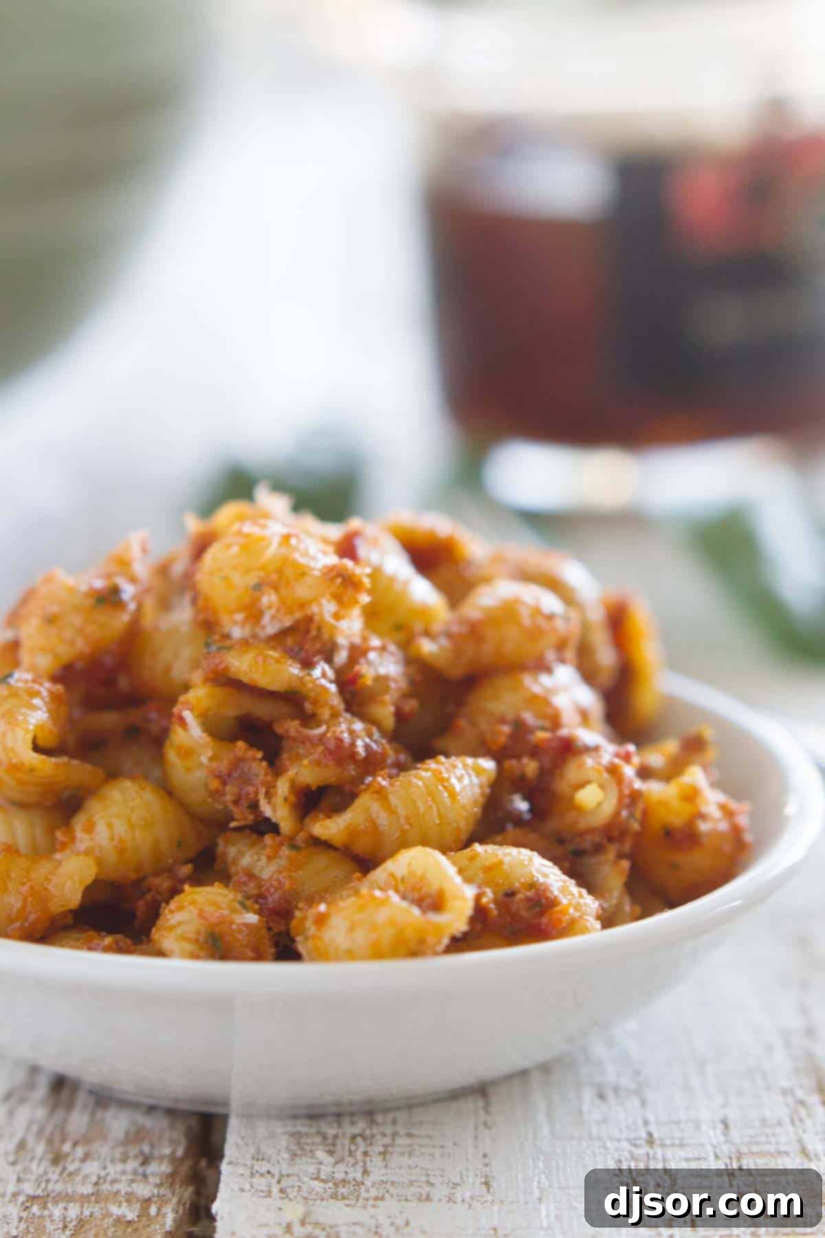 A vibrant Sun Dried Tomato Pesto Pasta Salad served in a elegant white bowl, garnished with fresh basil.