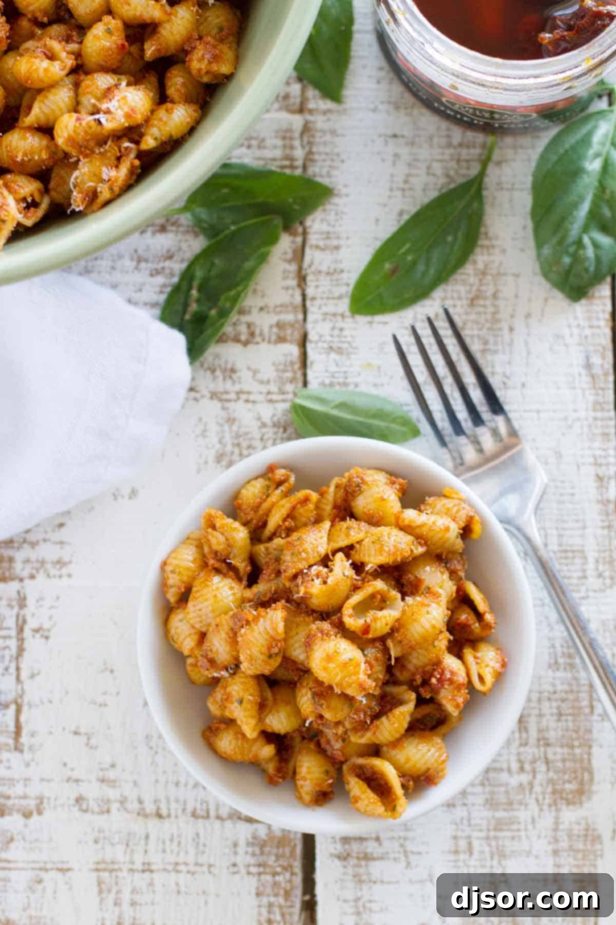 A closer view of Sun Dried Tomato Pesto Pasta Salad, showing the rich red pesto coating the pasta shells.