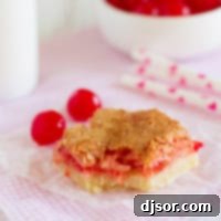 A close-up of a Coconut Cherry Almond Bar, showing the rich, chewy texture and the vibrant cherry pieces embedded within.
