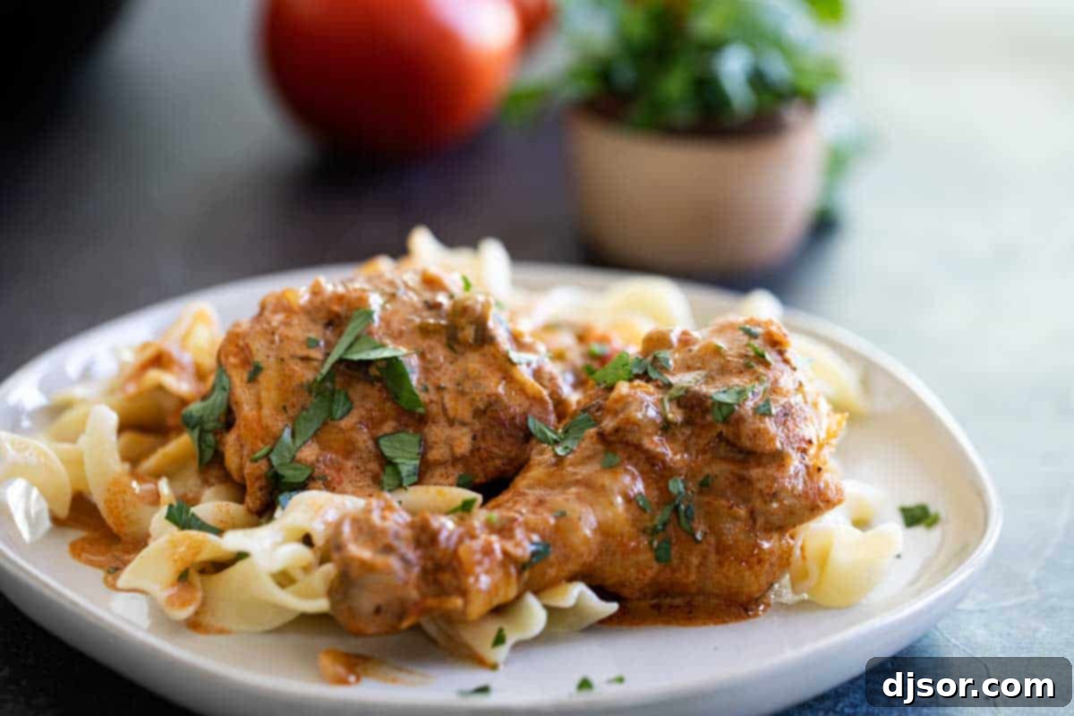 Rich, comforting and flavorful, this Chicken Paprikash is based off of a popular Hungarian recipe. It’s easy enough to make on a weeknight and is loved by both adults and children. plate with chicken paprikash over buttered noodles