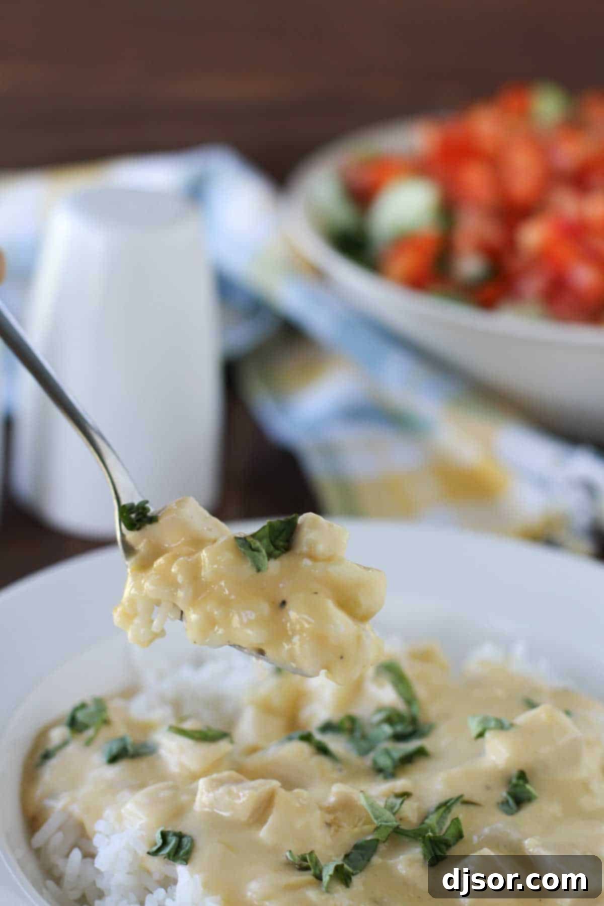 Taking a delicious bite of Cheesy Sour Cream Chicken. A fork taking a bite from a plate of Cheesy Sour Cream Chicken, showing the creamy texture and tender chicken pieces.