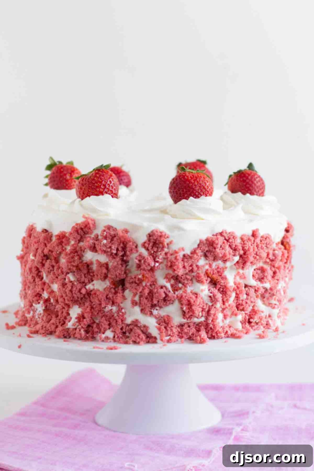 Strawberry Milkshake Ice Cream Cake: Layers of strawberry cake, strawberry ice cream, and sweetened whipped cream for a delicious treat. A stunning Strawberry Milkshake Ice Cream Cake on a cake stand, beautifully topped with fresh, vibrant strawberries, ready to be served.