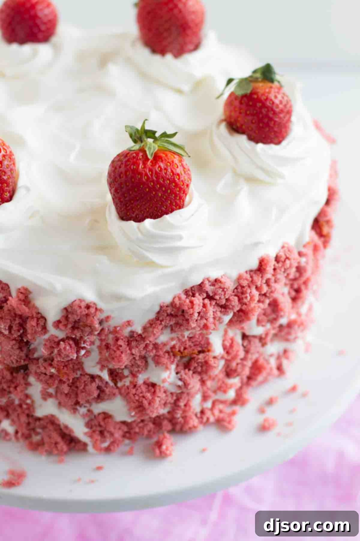Homemade Strawberry Milkshake Ice Cream Cake with fluffy whipped cream frosting. A close-up shot of a Strawberry Milkshake Ice Cream Cake, revealing its beautiful layered structure and a scattering of cake crumbs around the base, highlighting its homemade charm.