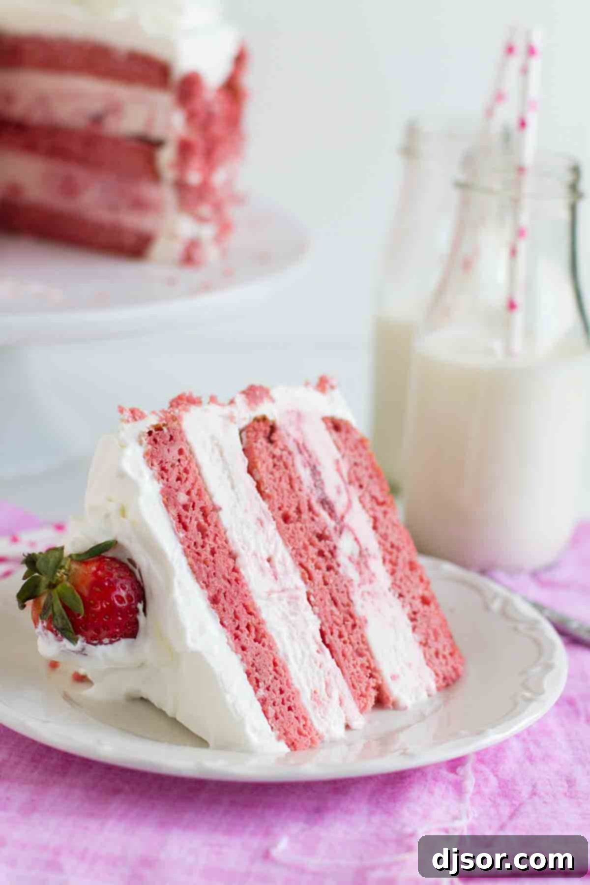 Enjoy a slice of homemade Strawberry Milkshake Ice Cream Cake. A perfectly portioned slice of Strawberry Milkshake Ice Cream Cake resting on a white plate, showcasing its distinct layers of cake and ice cream.