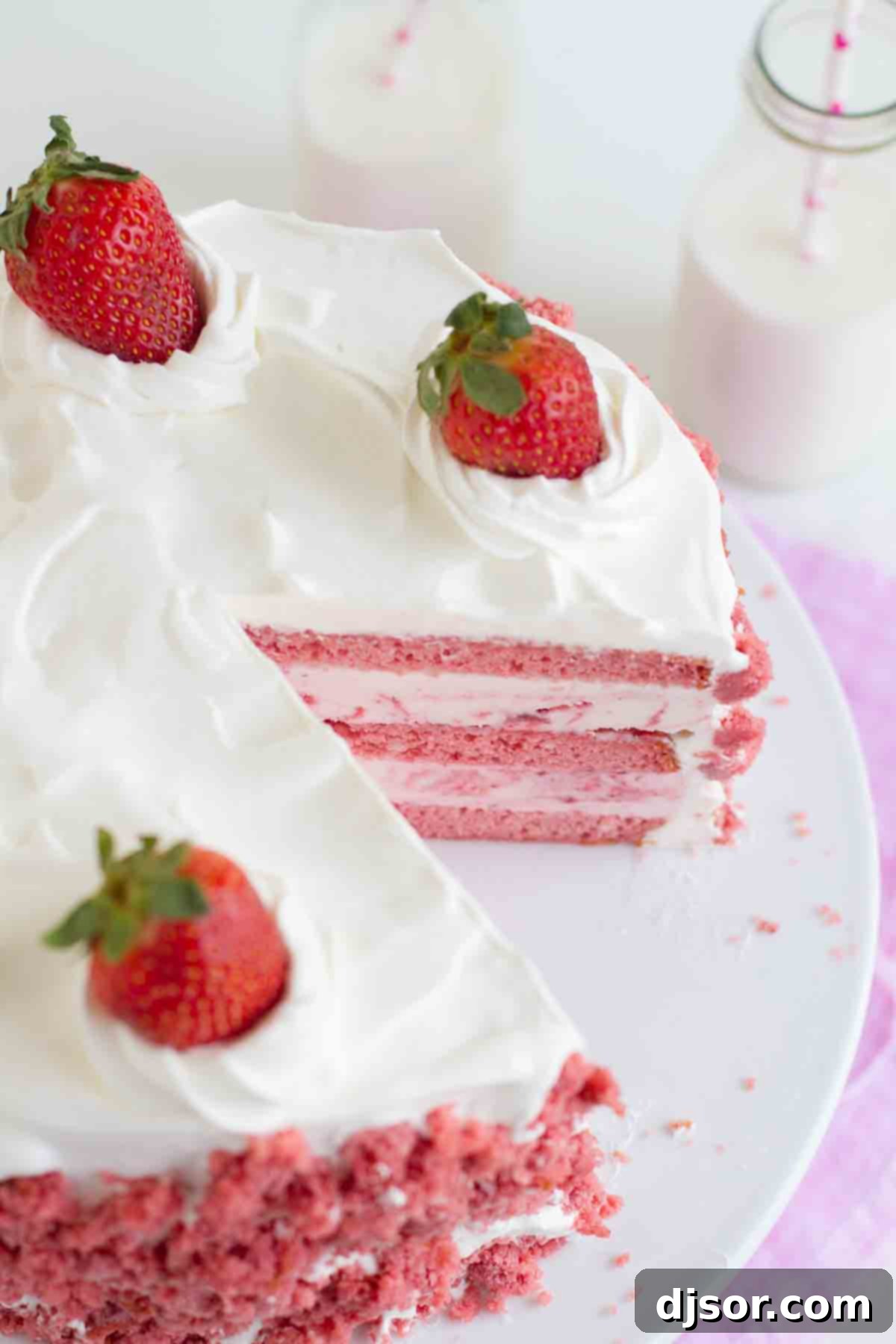 Strawberry Milkshake Ice Cream Cake, perfect for celebrations and sweet cravings. A stunning Strawberry Milkshake Ice Cream Cake with a slice already removed, revealing the delightful pink layers of cake and strawberry ice cream beneath a cloud of whipped cream.