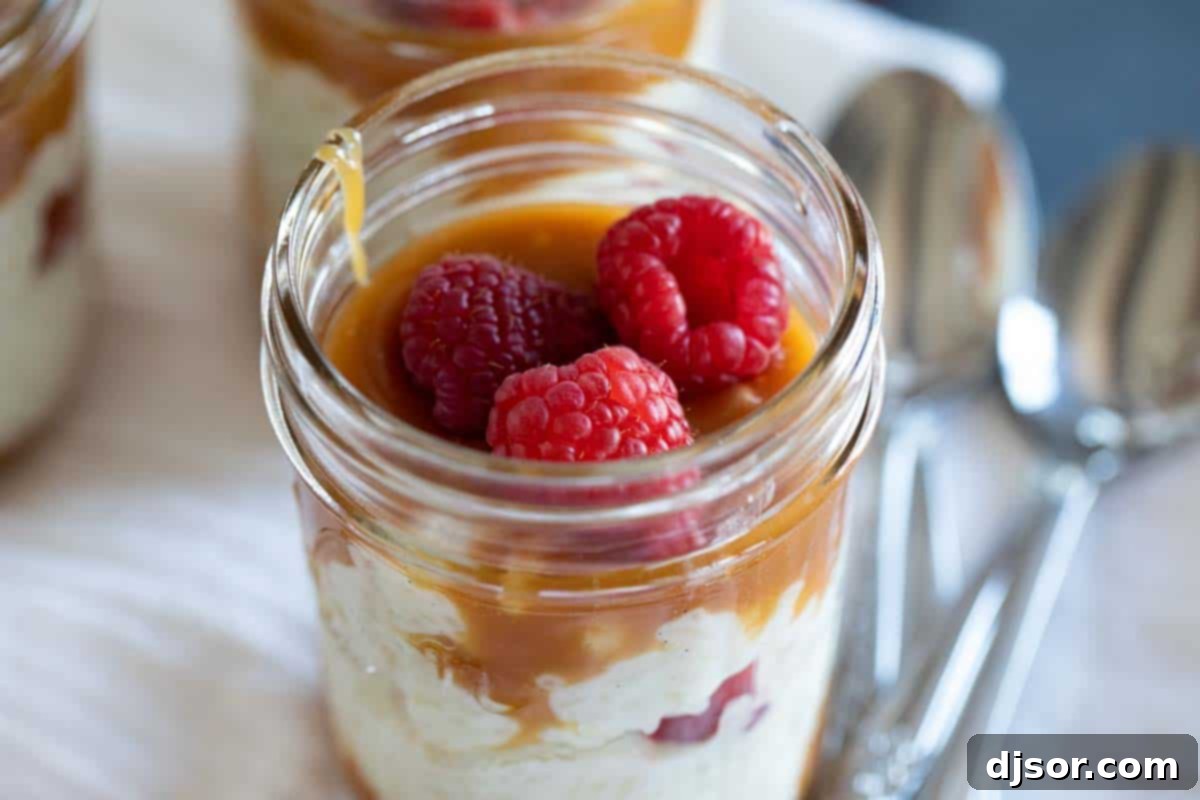 Jar with rice pudding topped with salted caramel and raspberries, showcasing an easy yet impressive dessert.