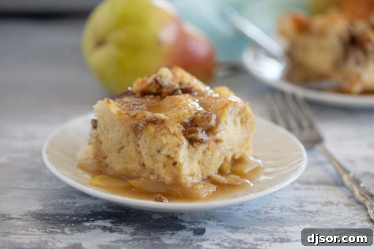A delectable slice of Pear Baked French Toast on a white plate, garnished with powdered sugar, with fresh pears in the soft-focus background.