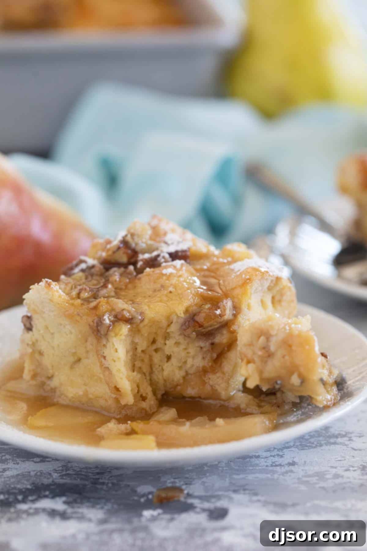 A close-up shot of a slice of Pear Baked French Toast with a bite taken, revealing its soft, custardy interior and tender pear pieces.
