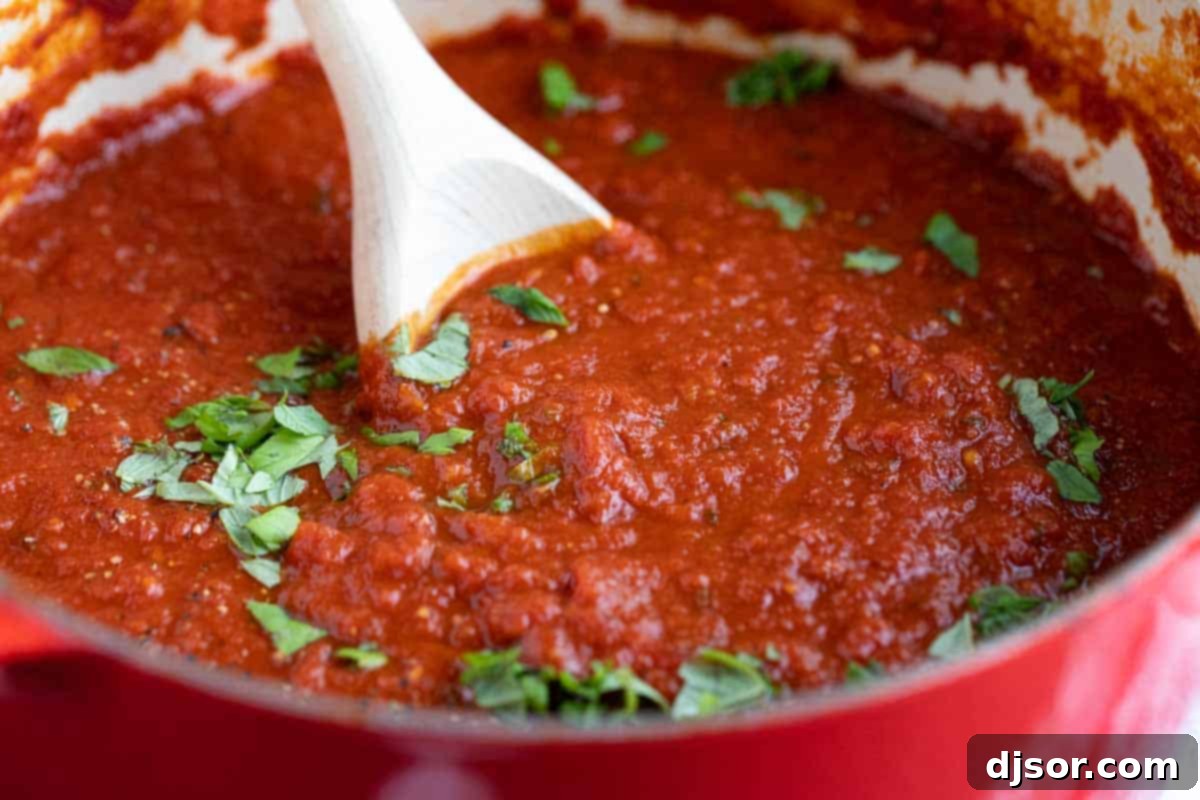 pot with homemade marinara sauce with fresh basil sprinkled on top, ready to be served.