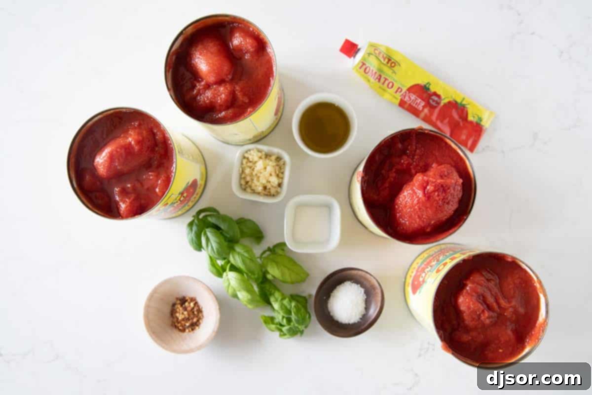A selection of fresh ingredients including olive oil, garlic, tomato paste, canned tomatoes, basil, salt, red pepper flakes, and sugar, all laid out for making homemade Marinara Sauce.