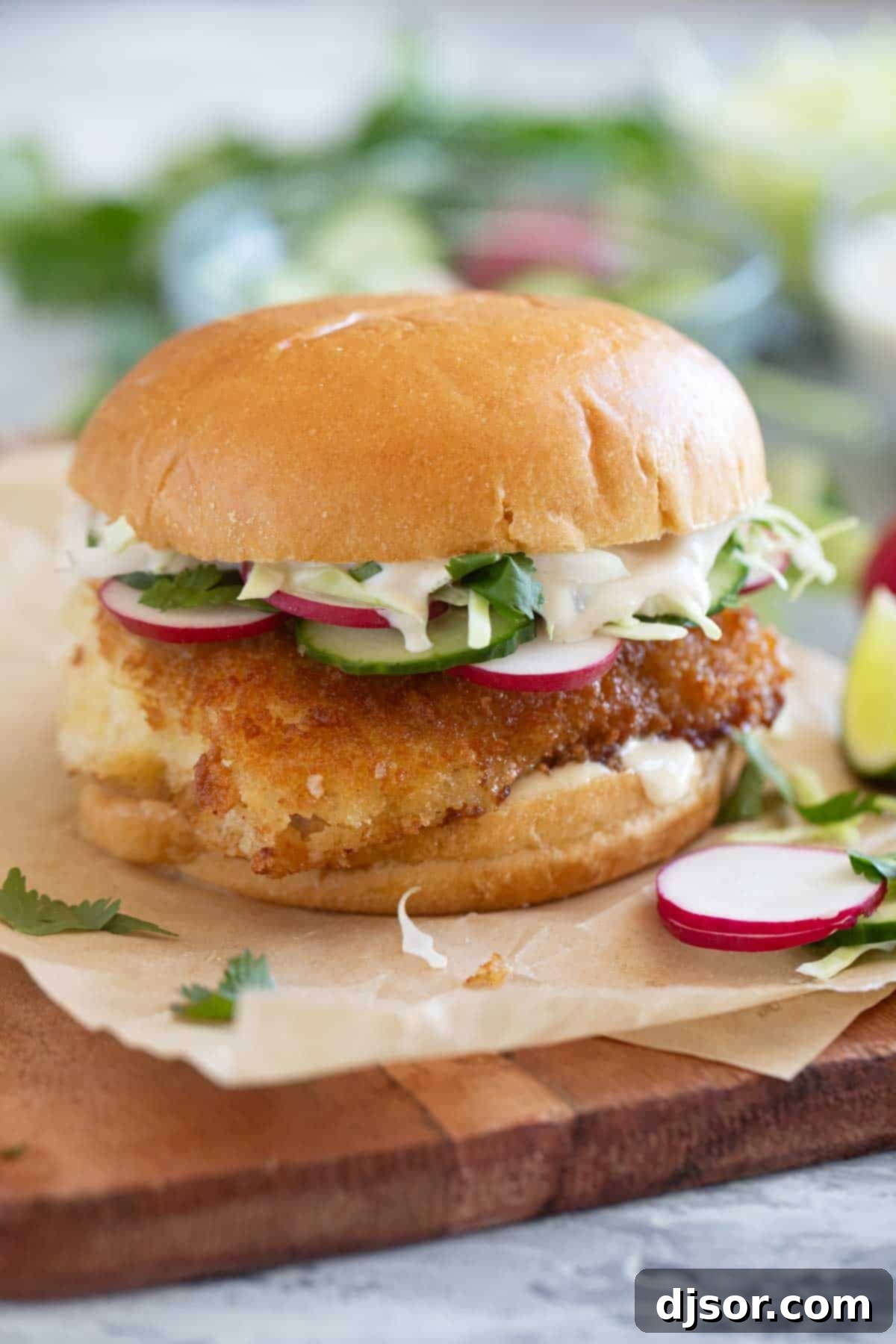 Crispy Fish Sandwich topped with cucumber, radish, cabbage, and homemade wasabi tartar sauce.
