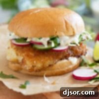 Crispy Fish Sandwich topped with cucumber, radish, cabbage, and homemade wasabi tartar sauce.