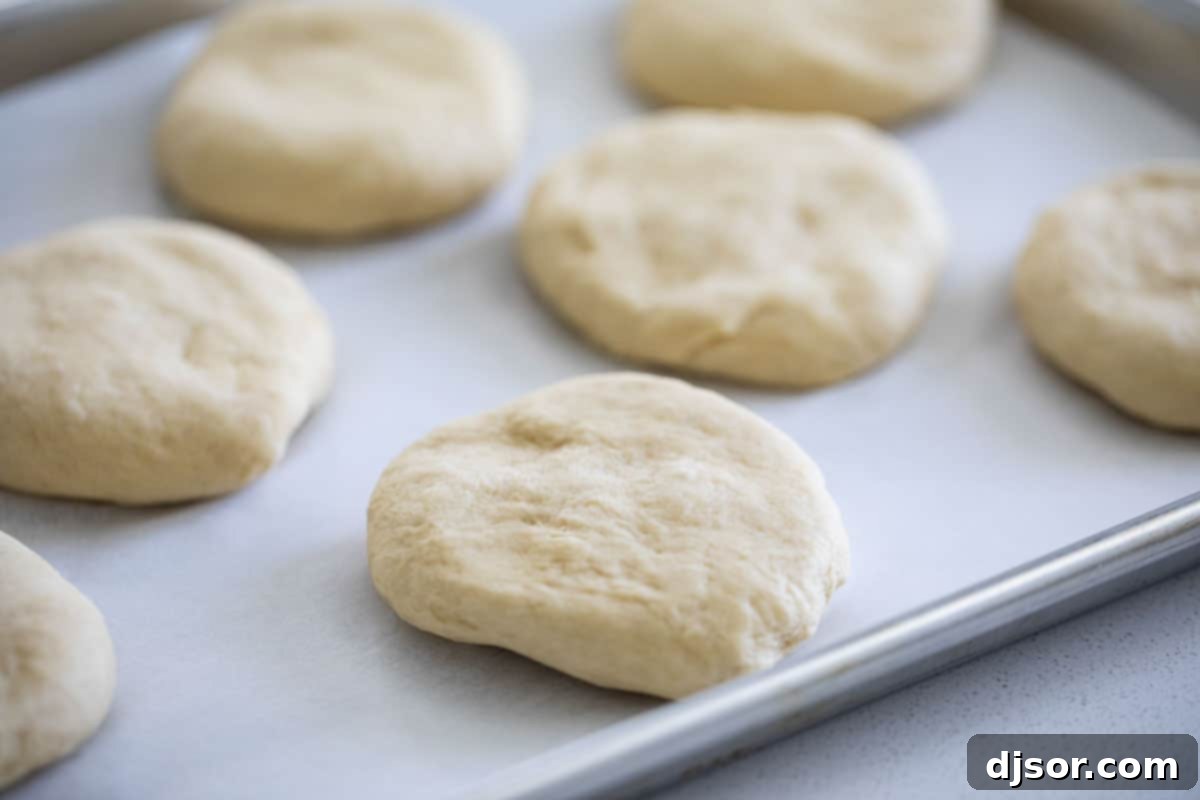Dough Ready for First Rise for the Best Homemade Hamburger Buns Smooth, elastic dough resting in a bowl, covered with a towel, undergoing its first rise for homemade hamburger buns.
