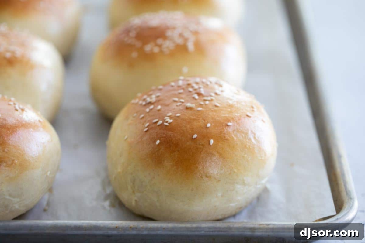 Golden Homemade Hamburger Buns Fresh from the Oven Freshly baked golden-brown hamburger buns cooling on a wire rack over a baking sheet, ready for assembly.