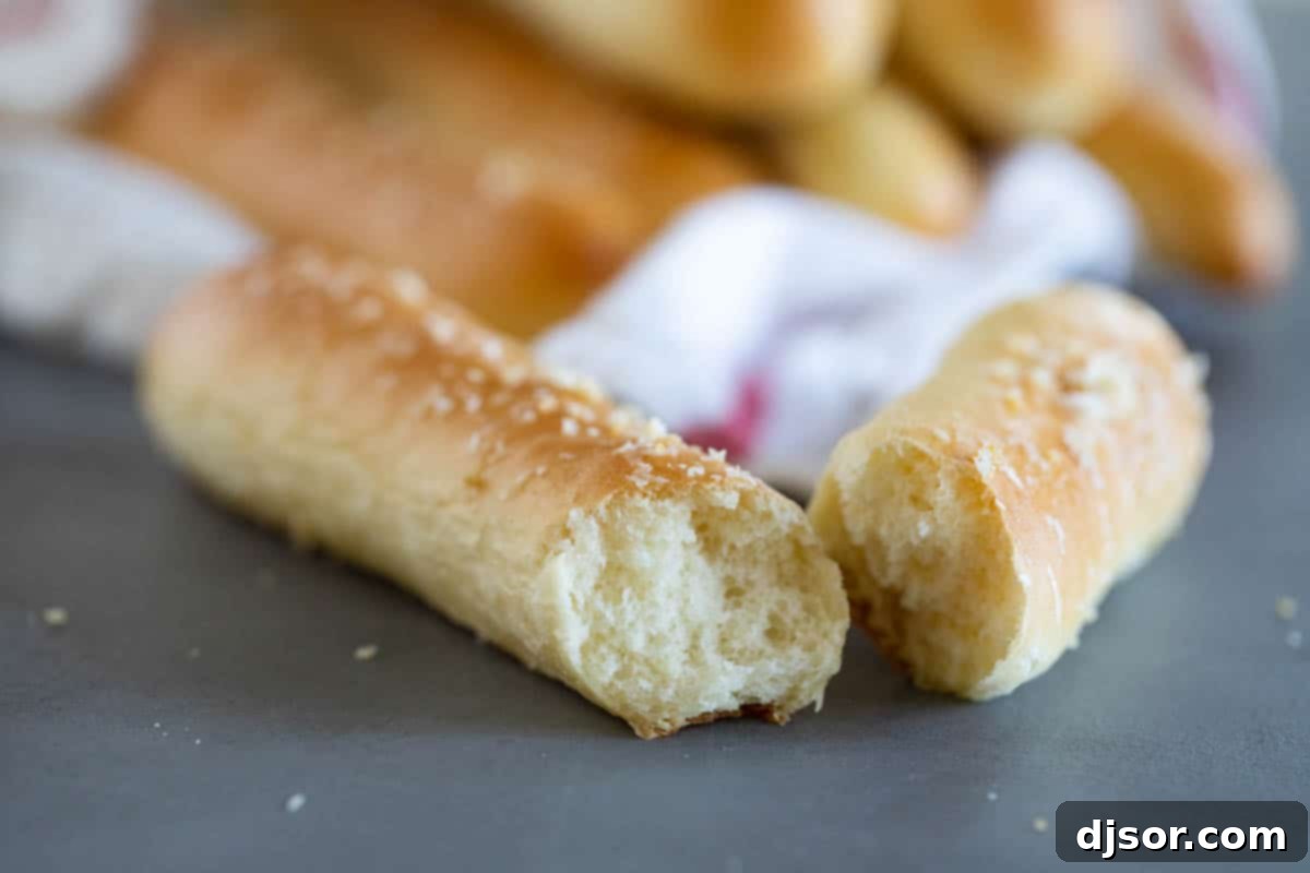 A perfectly baked breadstick broken in half, revealing its incredibly fluffy and tender interior.