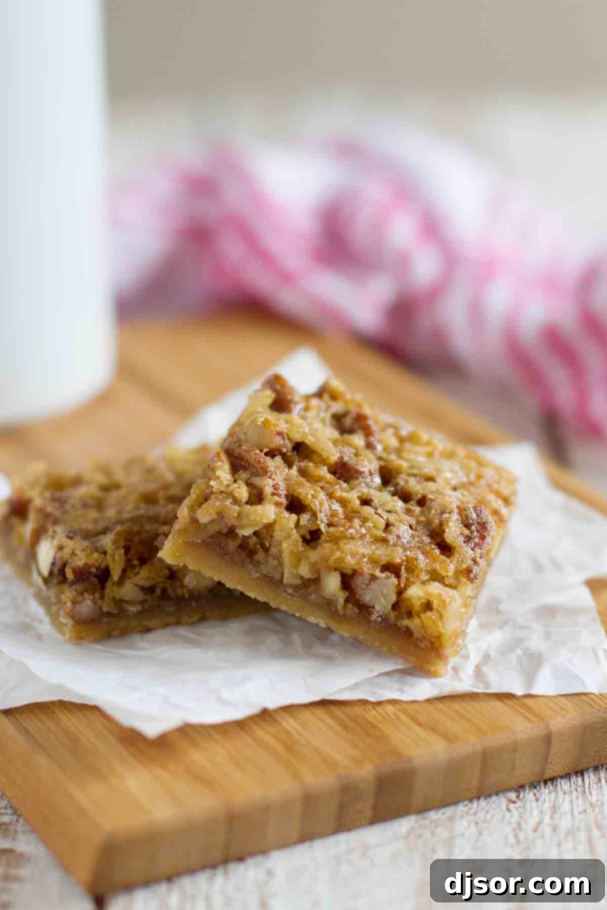 Two perfectly cut Coconut Pecan Bars on a rustic cutting board, highlighting their golden crust and rich, chewy topping.