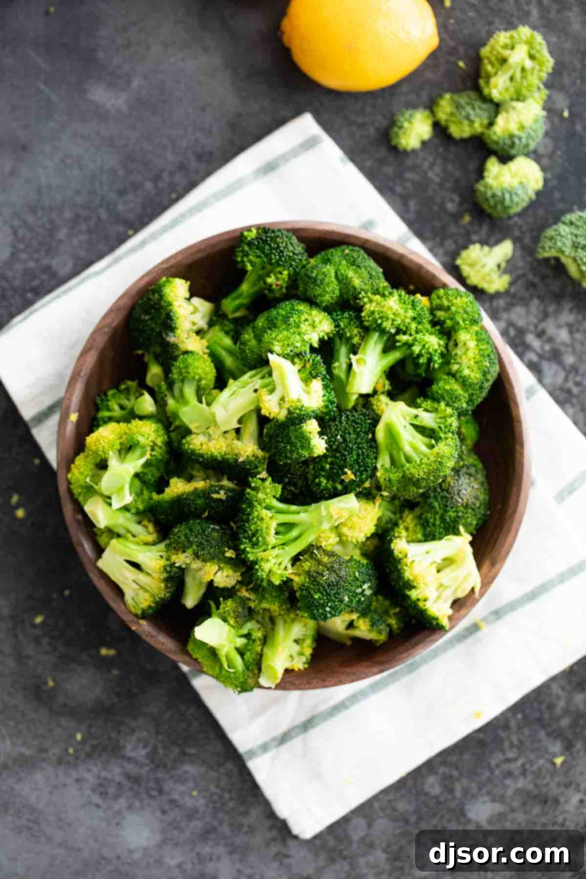 overhead view of lemon broccoli served in a white bowl with fresh lemon slices