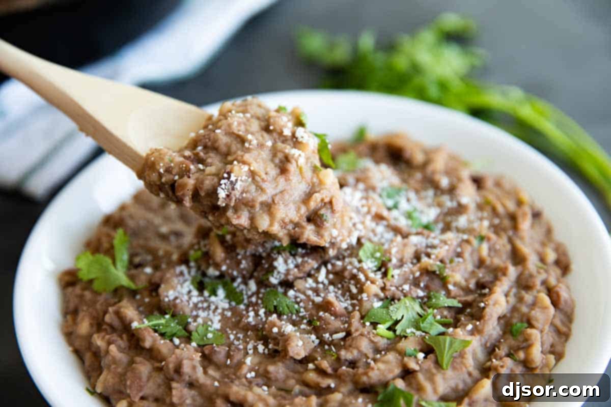 A vibrant bowl of homemade refried beans, garnished with fresh cilantro, ready to be served as a delicious side dish.