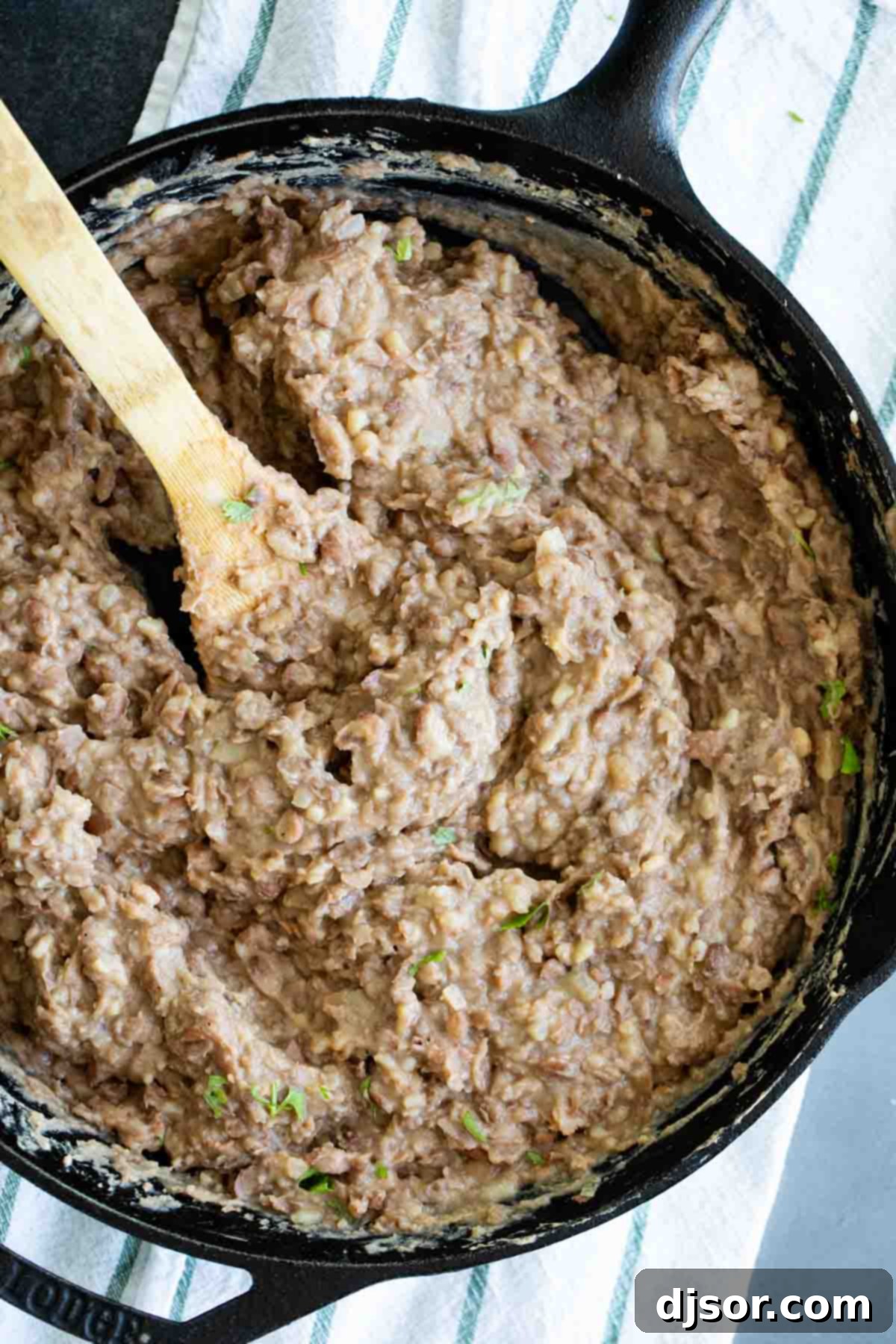 An inviting overhead view of freshly made refried beans in a rustic cast iron skillet, ready to be served.