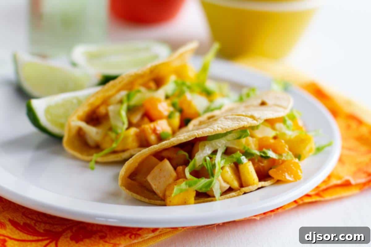 Fish tacos take a tropical turn with these Citrus Fish Tacos that are topped with a fruity, tropical salsa. Two vibrant Citrus Fish Tacos artfully arranged on a plate, garnished with fresh lime wedges, showcasing the colorful tropical salsa topping.