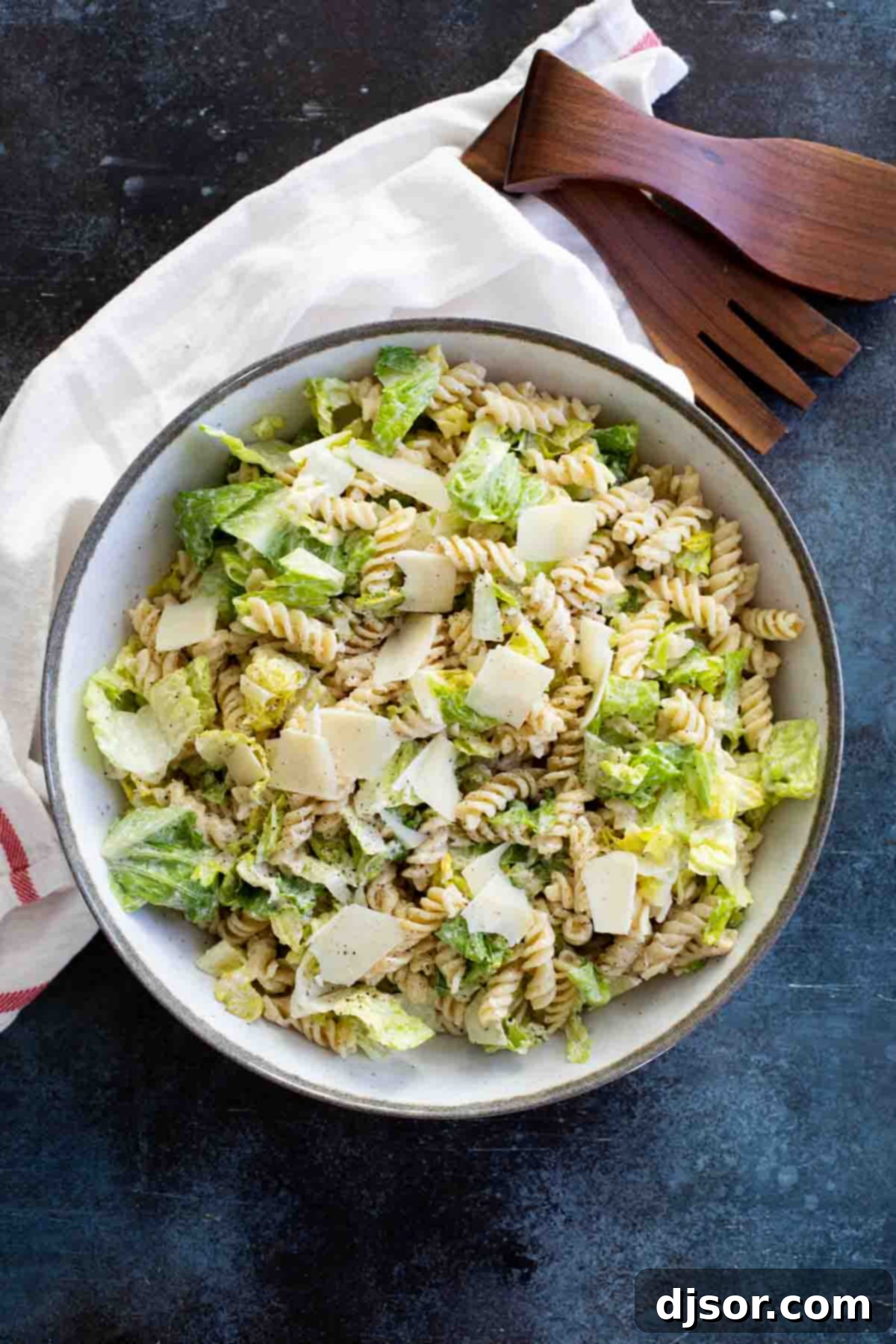Caesar Salad with rotini pasta in a large salad bowl, showcasing a hearty mix of greens and pasta.