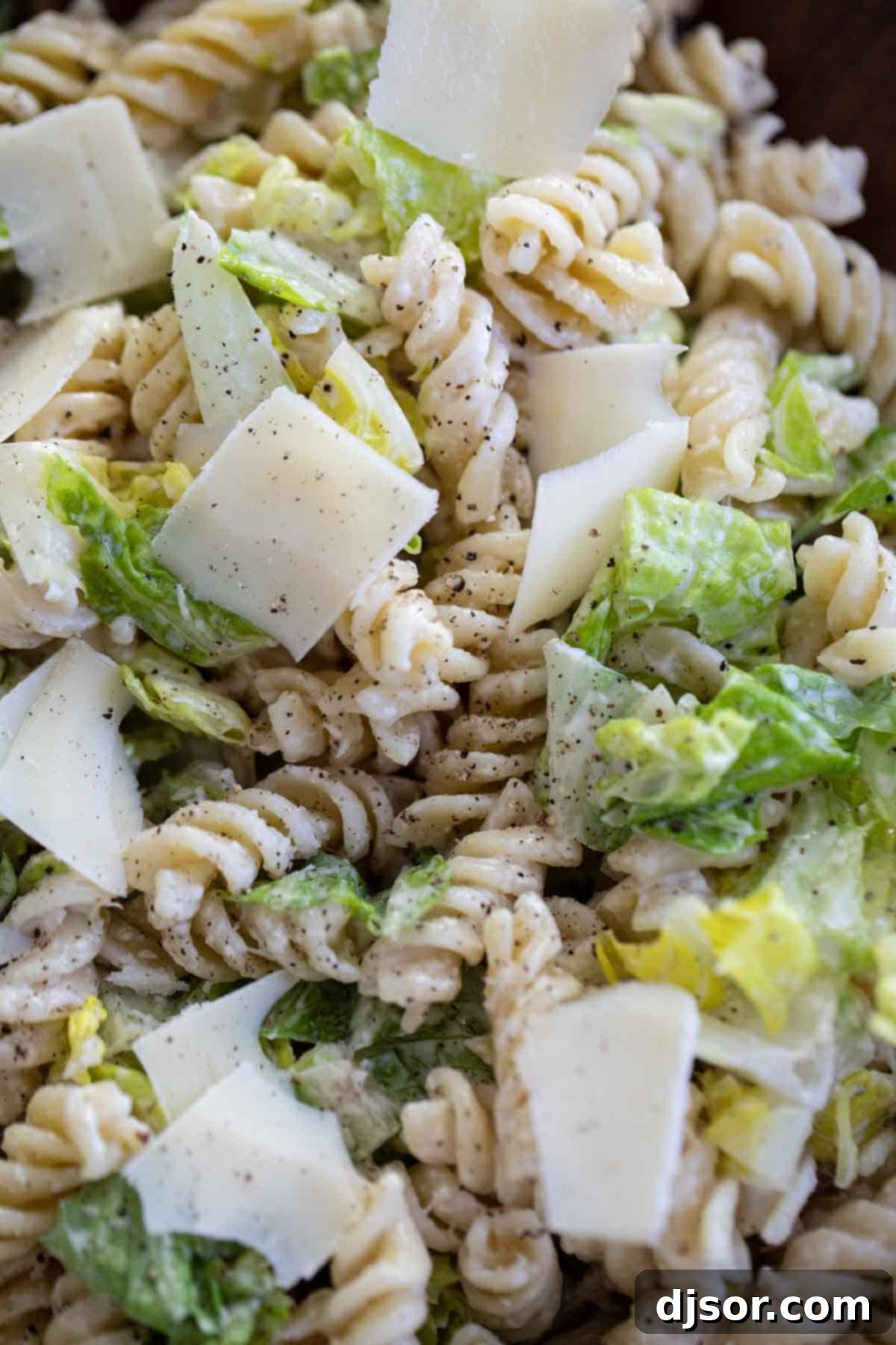 Close up of Caesar Salad with Pasta, sprinkled with Parmesan cheese.