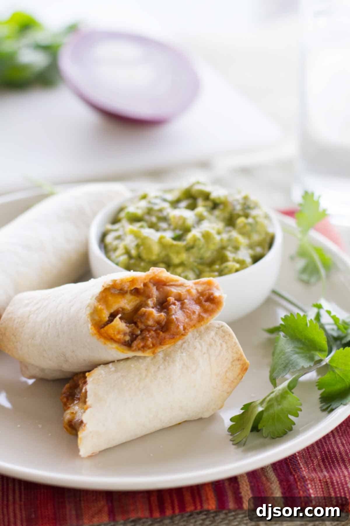 A plate featuring two golden-baked Mexican Egg Rolls, garnished with fresh cilantro and served alongside a vibrant bowl of Enchilada Guacamole.