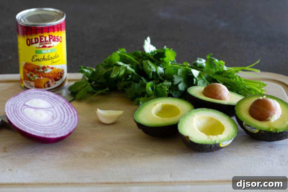 A vibrant flat lay of fresh ingredients for Baked Mexican Egg Rolls including ground beef, taco seasoning, refried beans, cheese, flour tortillas, avocados, red onion, cilantro, and lime.