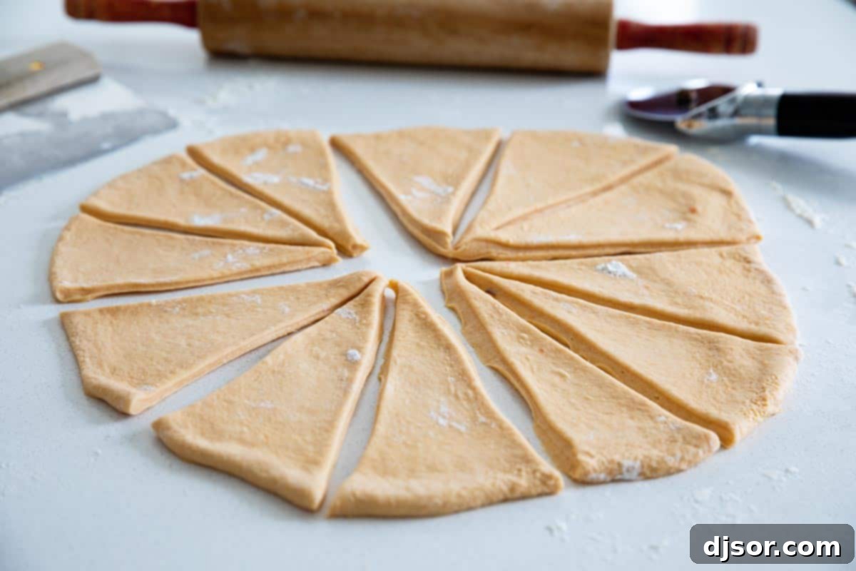 Soft and fluffy and slightly sweet, these Sweet Potato Buttermilk Crescent Rolls are perfect for a holiday. These homemade crescent rolls are so much better than store bought! rolling out and cutting dough for homemade crescent rolls