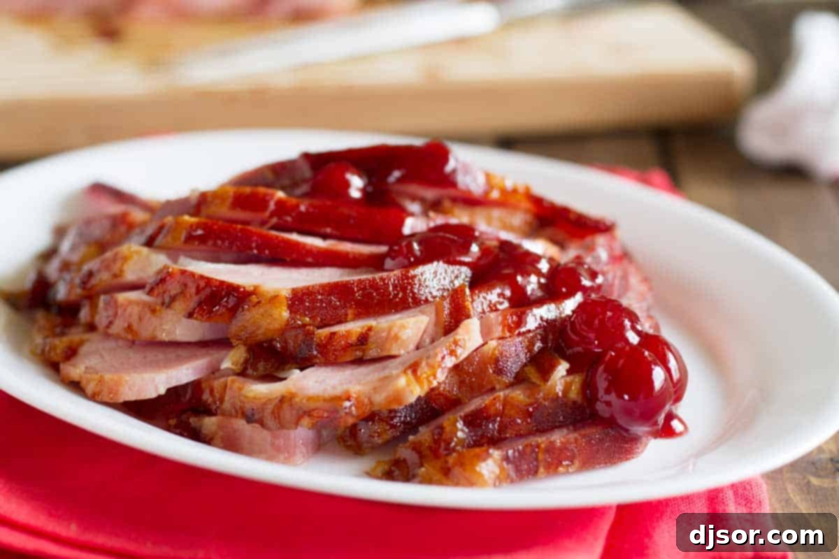 A beautifully cooked Brown Sugar and Cherry Glazed Ham, garnished with fresh cherries, on a serving platter, ready for a holiday meal.