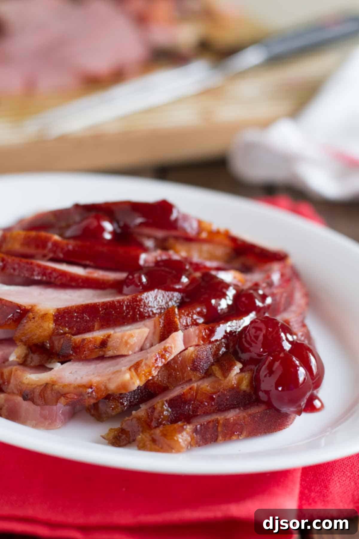 A stunning Brown Sugar and Cherry Glazed Ham presented whole on an elegant serving platter, ready to be carved and enjoyed as the centerpiece of a festive meal.