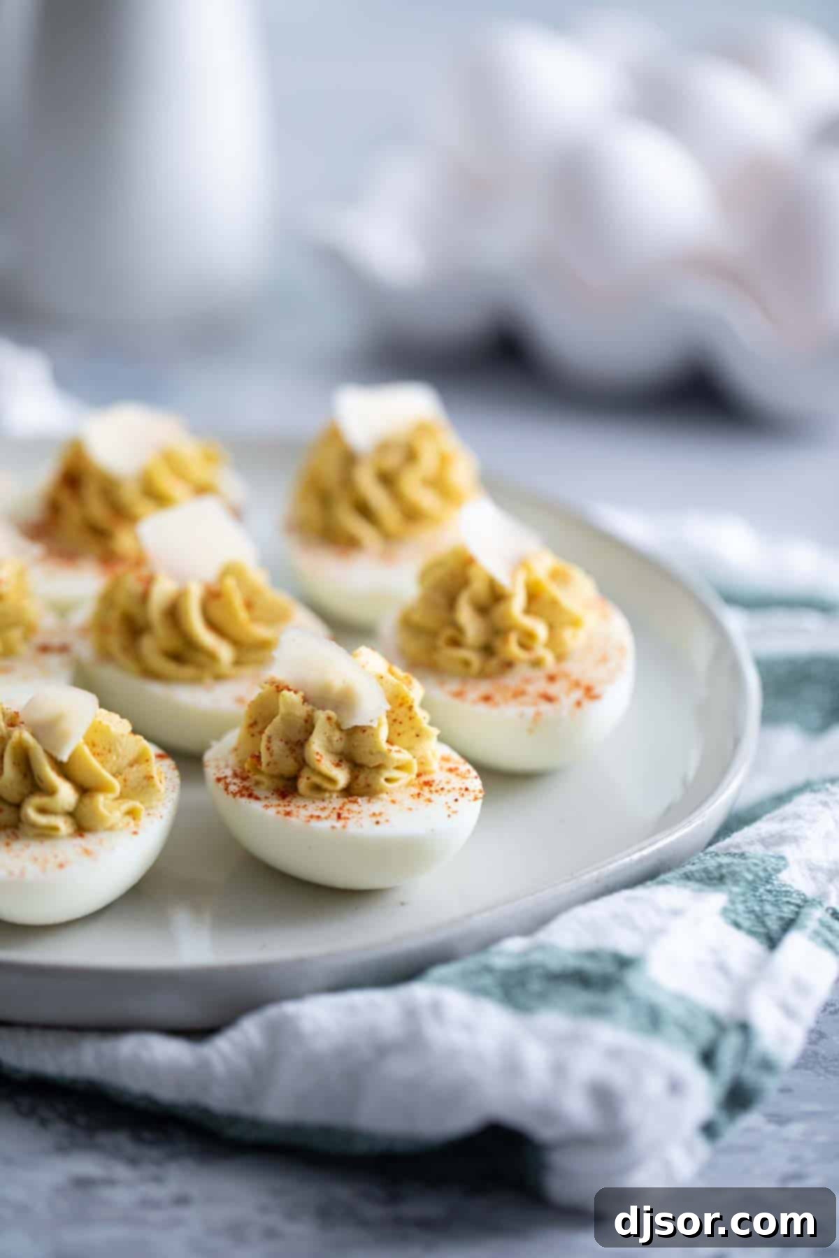 Love Caesar salad? This Caesar deviled eggs recipe has all of the flavors of that Italian salad, but in a creamy, delicious deviled egg. These are a fun, different appetizer! Caesar Deviled Eggs Recipe - A platter of deviled eggs garnished with Parmesan curls and paprika