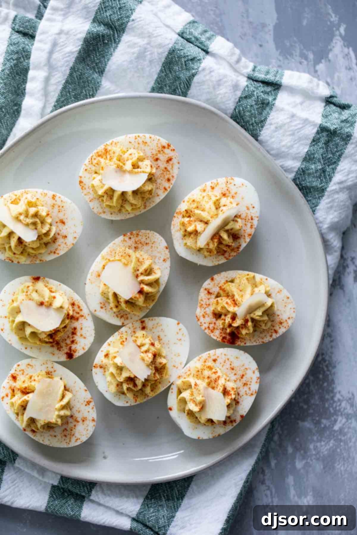 Love Caesar salad? This Caesar deviled eggs recipe has all of the flavors of that Italian salad, but in a creamy, delicious deviled egg. These are a fun, different appetizer! Overhead view of Caesar Deviled Eggs arranged on a serving plate