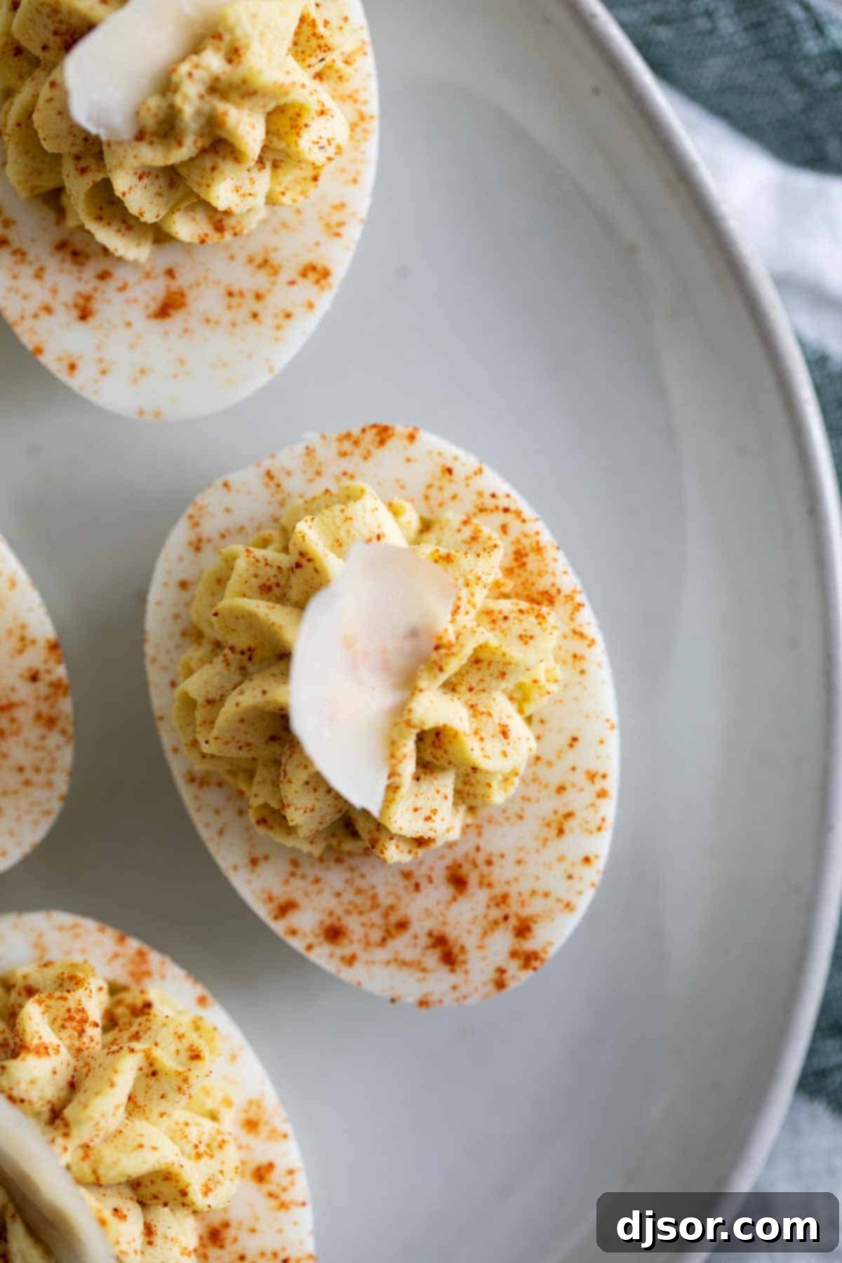 Love Caesar salad? This Caesar deviled eggs recipe has all of the flavors of that Italian salad, but in a creamy, delicious deviled egg. These are a fun, different appetizer! Close-up shot of Caesar Deviled Eggs revealing the creamy filling and Parmesan garnish