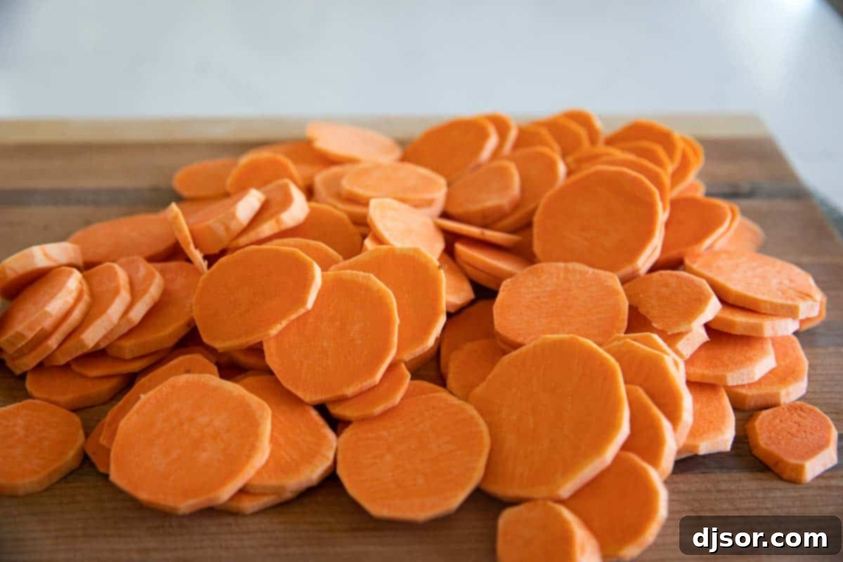 Creamy and cheesy, these Scalloped Sweet Potatoes are an easy addition to any holiday table. Layers or slice sweet potatoes are covered in cream and cheese in this indulgent savory side dish. Peeled and thinly sliced sweet potatoes neatly arranged on a wooden cutting board, ready for layering.