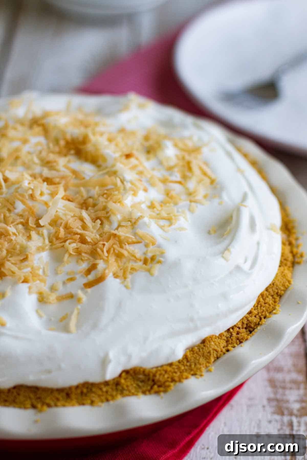 A stunning whole Coconut Cream Pie, showcasing its unique and perfectly baked cookie crust, ready to be sliced and enjoyed. whole coconut cream pie with a golden brown cookie crust