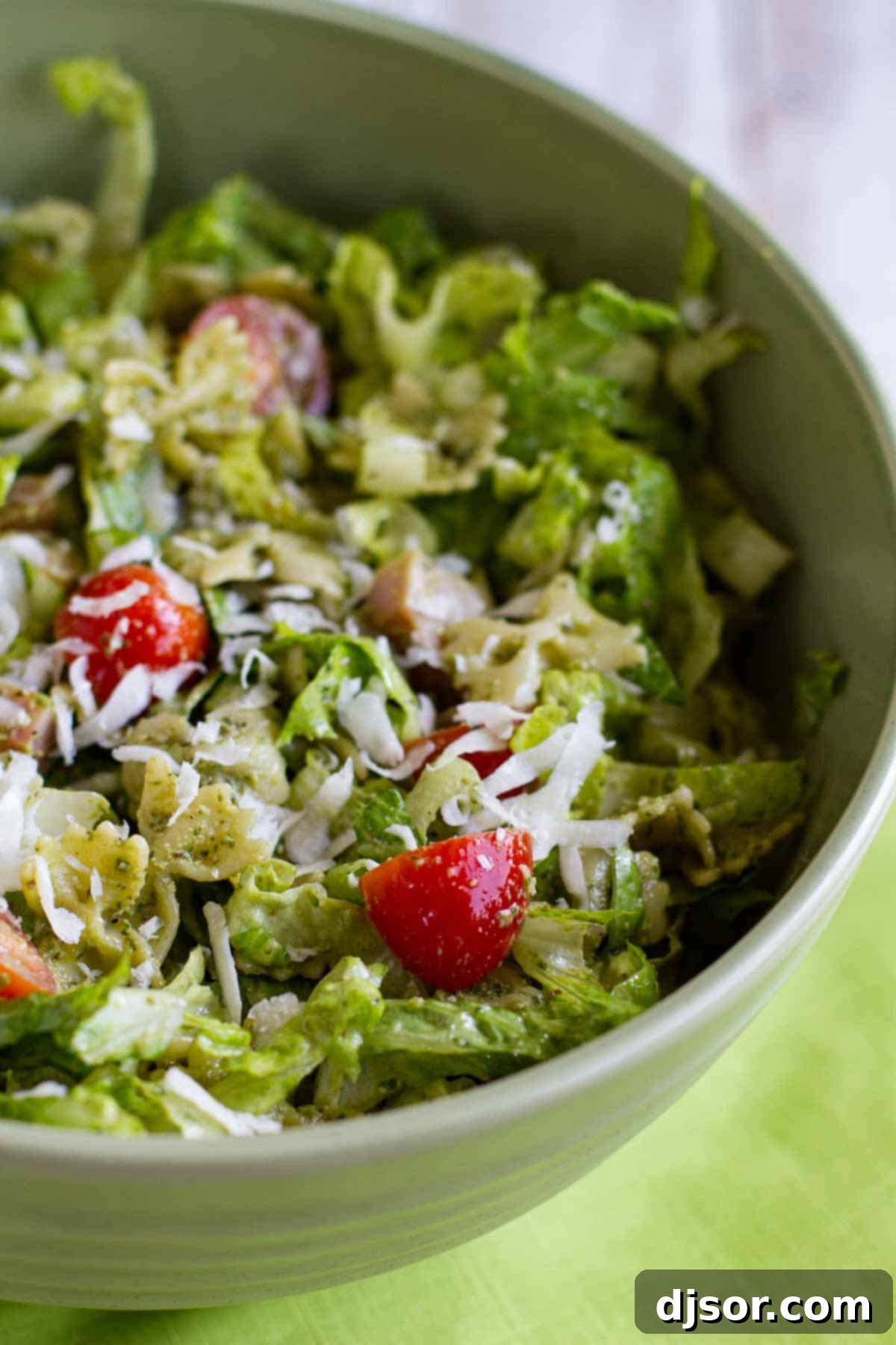 Pesto Pasta with Ham Salad 2 A large bowl brimming with fresh Pesto Pasta and Ham Salad, showcasing vibrant green romaine, diced ham, bright red tomatoes, and pasta generously coated in walnut pesto.